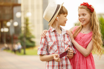 Little boy and girl using smart phone together outdoors