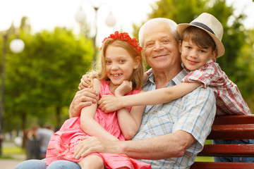 Happy senior man relaxing outdoors with his grandkids
