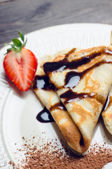 Russian thin pancakes (blini), with strawberry and chocolate sauce. Selective focus.