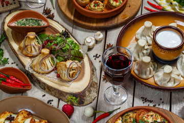 View from above of georgian cuisine on brown wooden table. Traditional georgian cuisine and food - khinkali, kharcho, chahokhbili, phali, lobio and local sauces - tkemali, satsebeli, adzhika. Top view