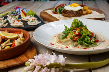 View from above of georgian cuisine on brown wooden table. Traditional georgian cuisine and food - khinkali, kharcho, chahokhbili, phali, lobio and local sauces - tkemali, satsebeli, adzhika. Top view