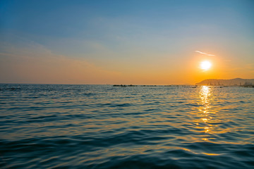 Gorgeous seascape. Beautiful sunset reflected in the waves. Silhouettes of mountains and ships on the horizon. Porto Di Marina Di Pisa, Italy.