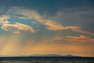 Naklejka na ściany i meble Beautiful seascape. Majestic sunset and rain over the sea. Silhouettes of mountains on the horizon. Follonica Beaches in Maremma Tuscany, Italy.