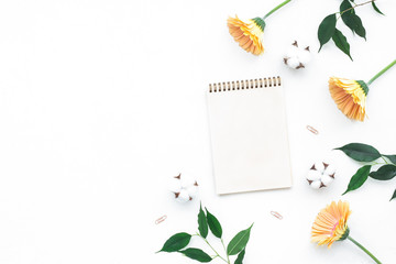 Notebook, ficus leaves, gerbera flowers on white background, flat lay, top view
