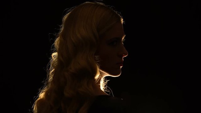 Seductive blonde lady looking with contempt to side isolated on black background