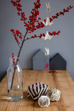 Wrapped present, paper decoration and twig of holly in vase