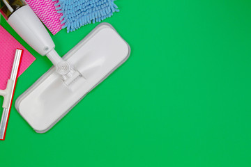 Housework, housekeeping, household, cleaning service concept. Cleaning spray mop, window cleaner, rags and sponges on green background
