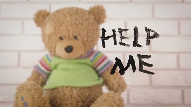 Difficult childhood. Help me. A teddy bear asks for help. Child abuse concept.