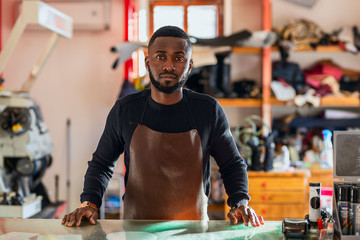 Young cheerful shoemaker in workshop.