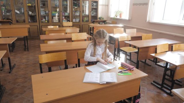 Little girl sitting and studying at school class.