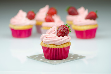 Delicious pink strawberry cupcake with a strawberry. Cupcakes and pink icing with a strawberries on top