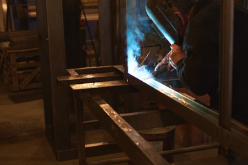 welder welds a metal frame for the power plant.