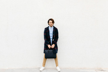 Portrait of confident man with a briefcase standing at a wall
