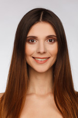 Portrait of a beautiful woman with straight long hair and interesting emotion. Light gray background