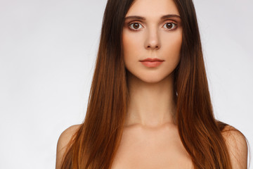 Fototapeta premium Portrait of a beautiful woman with straight long hair and interesting emotion. Light gray background