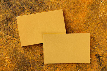 Mockup of golden foil blank business cards stack and single business card at textured yellow luxury...