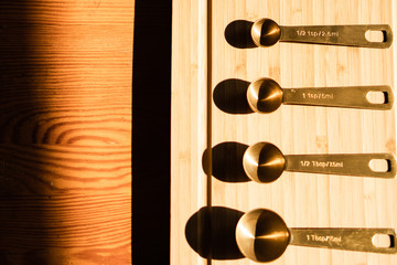 Golden kitchen scoops arranged in a line on a wooden chopping board. Kitchen scoops have capacity...
