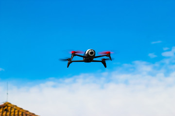 Drone flying overhead in cloudy blue sky