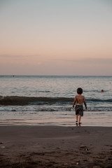 Naklejka premium Niño mirando el mar mientras atardece