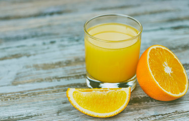 a glass of fresh orange juice with fresh citrus fruits on a light wooden table. horizontal view. citrus juice