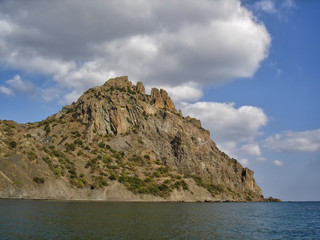 Fototapeta na wymiar Karadag (Black Mountain) - extinct volcano in Crimea, famous for its bizarre rock formations. View from the sea in sunny day of golden autumn