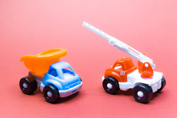 Fototapeta premium Colorful toy truck and fire truck on a pink background