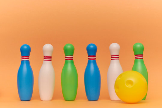 skittles and a ball for playing bowling on a peach background with copy space. Kids toys.
