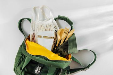 Green backpack with mesh market bag, bamboo cutlery  and  reusable coffee mug. Sustainable lifestyle. Zero waste, plastic free concept.