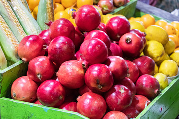 Group of pomegranates on a wooden crate together with lemons in the Male market in Maldives