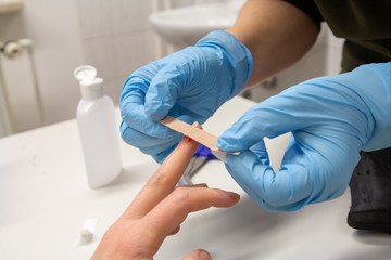 Diabetes patient measuring glucose level blood test using ultra mini glucometer and small drop of blood from finger and test strips isolated on a white background