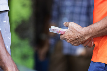 The hands of a man holding money (rufiyaa) trading with another man outdoors