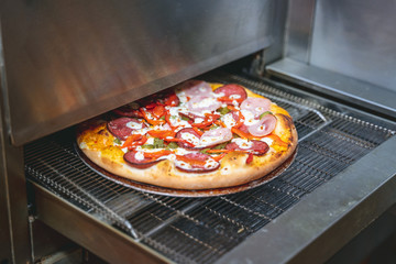 Fresh cooked pizza modern industrial oven in a restaurant 