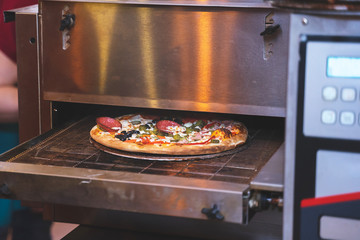 Fresh cooked pizza modern industrial oven in a restaurant 
