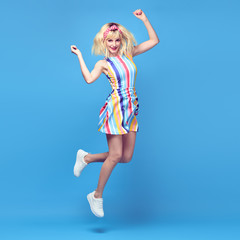 Obraz na płótnie Canvas Young fashionable girl Smiling jump in Studio. Beautiful easy-going blonde woman in Stylish summer dress having fun, makeup, Trendy sneakers. Cheerful happy model, funny fashion concept