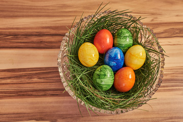 Bunte Ostereier in grünem Heu mit Holz Hintergrund