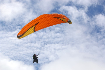 Tandem paraglider flying orange wing