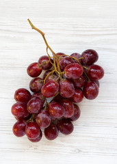 Bunch of ripe red grape on white wooden table, top view. Overhead, from above.