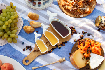set of three white sauceboats with sweet honey on wooden tray at picnic food lay out background