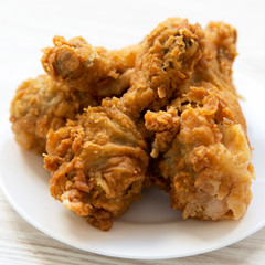 Fried chicken drumsticks on a round white plate, side view. Close-up.
