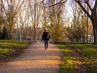 A senior woman with white hair listening to music with headphones walking in an urban park