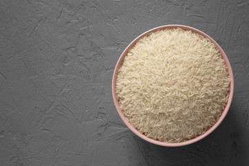 Top view, dry white rice basmati in a pink bowl over gray surface. Flat lay, overhead, from above. Copy space.