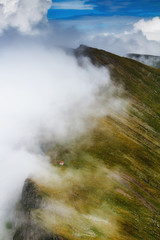 Amazing landscape of summer mountains. View of fog and low clouds over Fagaras Mountains are the highest mountains of the Southern Carpathians. Transylvania. Romania. Travel background. 