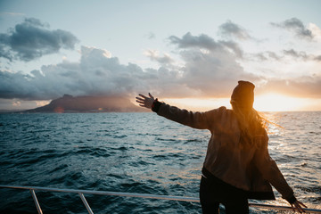South Africa, young woman with woolly hat during boat trip at sunset