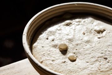 Sourdough bread proofing in a basket with visible gas bubbles. Homemade baking.