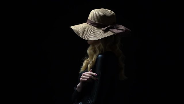 Anonymous lady in hat seductively stroking her body against dark background