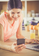 Young woman in kitchen with laptop computer looking recipes, smiling. Food blogger concept.