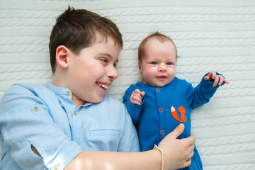 Big brother hugging his newborn baby girl. Toddler kid meeting new sibling