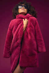 curly model in a fur coat posing on a bright background