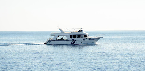 White yacht in the blue sea against a clear blue sky background.