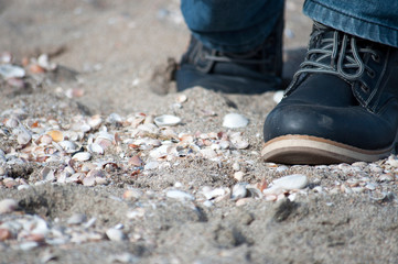 Man legs in hsoes wolking on a sand beach